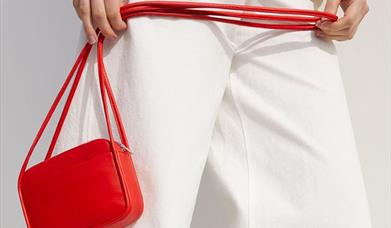 Woman in white holding a red handbag