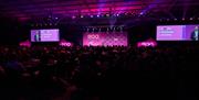 Event room filled full of people watching the screen